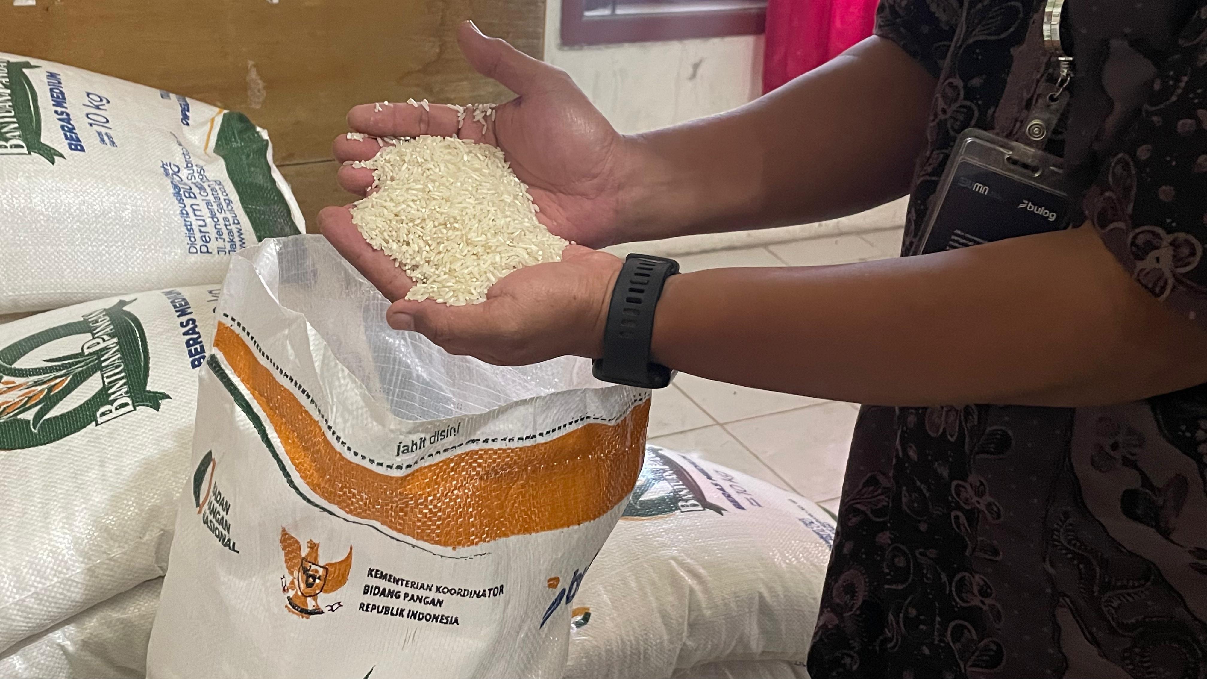 BANTUAN: Petugas Bulog Pati menunjukkan kualitas beras bagus saat kegiatan pembagian bantuan di Balai Desa Genjahan, Kecamatan Jiken, Kamis (31/7). (RAHUL OSCARRA DUTA/RADAR BOJONEGORO)