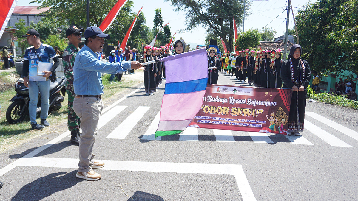 Camat Kanor, Faisol Ahmadi (memegang bendera) melepas peserta Karnaval Kemerdekaan Kecamatan Kanor 2025 pada Minggu (31/8). (YUAN EDO/RADAR BOJONEGORO)