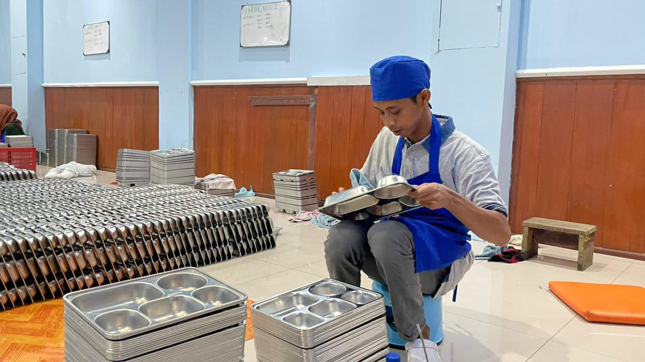 SEMANGAT: Andy Setioaji, seorang difabel yang setiap harinya penuh semangat mencuci ratusan hingga ribuan ompreng di SPPG Klopoduwur, Kecamatan Banjarejo.