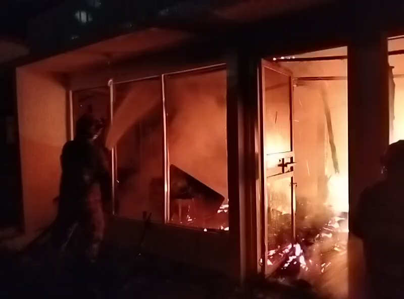Petugas Dindamkarmat Bojonegoro mencoba memadamkan api dari pintu masuk kafe pada Selasa dinihari (13/11) (ISTIMEWA/RADAR BOJONEGORO)