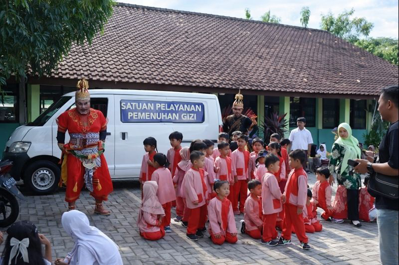 MENGHIBUR: Sopir SPPG mengenakan cosplay tokoh wayang saat mengangarkan menu MBG.