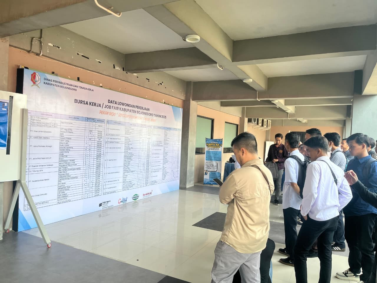 LOKER: Para pancari kerja sedang melihat daftar informasi lowongan kerja saat pelaksanaan Jobfair 2025 di GOR Utama Bojonegoro.