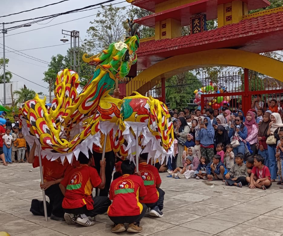 MEMUKAU: Warga tampak menikmati kemeriahan barongsai dan liong yang tampil di halaman kelenteng di Hok Swie Bio Bojonegoro dalan perayaan Tahun Baru Imlek 2577.