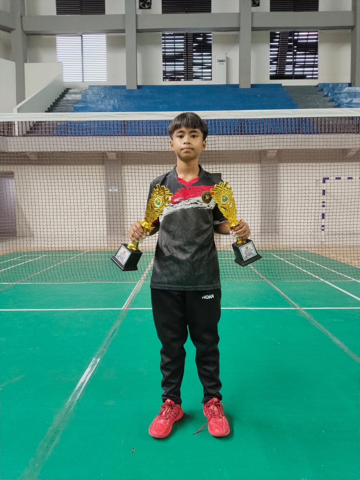 JUARA: Brilian Umay Satriadi menunjukkan paiala kejuaraan badminton.