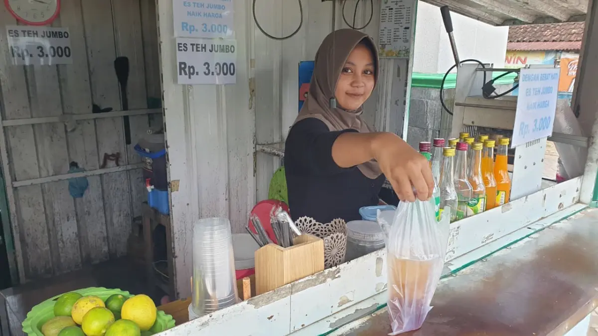 PALING TERDAMPAK: Penjual es teh di Desa Sumberarum, Kecamatan Dander saat melayani pembeli. Kenaikan harga plastik kemasan membuat pelaku usaha dilema, menaikkan harga atau memangkas porsi. (HAKAM ALGHIVARI/RADAR BOJONEGORO)