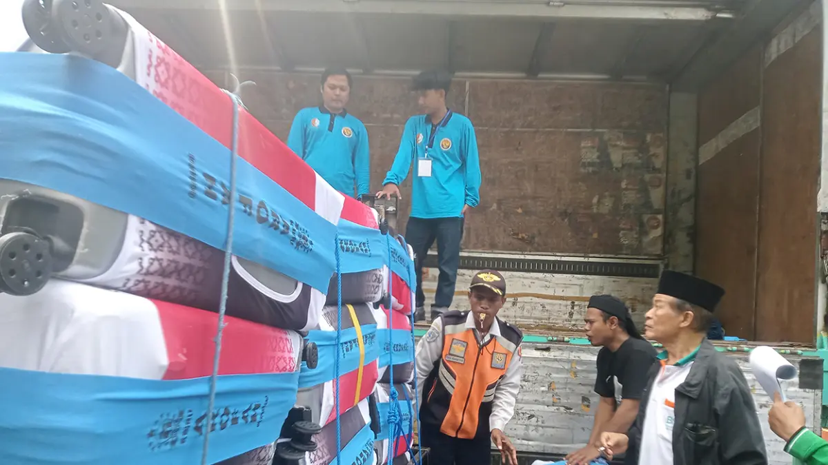 KOPER CJH: Petugas sedang mengakut koper CJH Bojonegoro, karena jalan menuju Embarkasi Surabaya rawan kemacetan di Lamongan, dialihkan via Jombang. (M. IRVAN RAMADHON/RADAR BOJONEGORO)