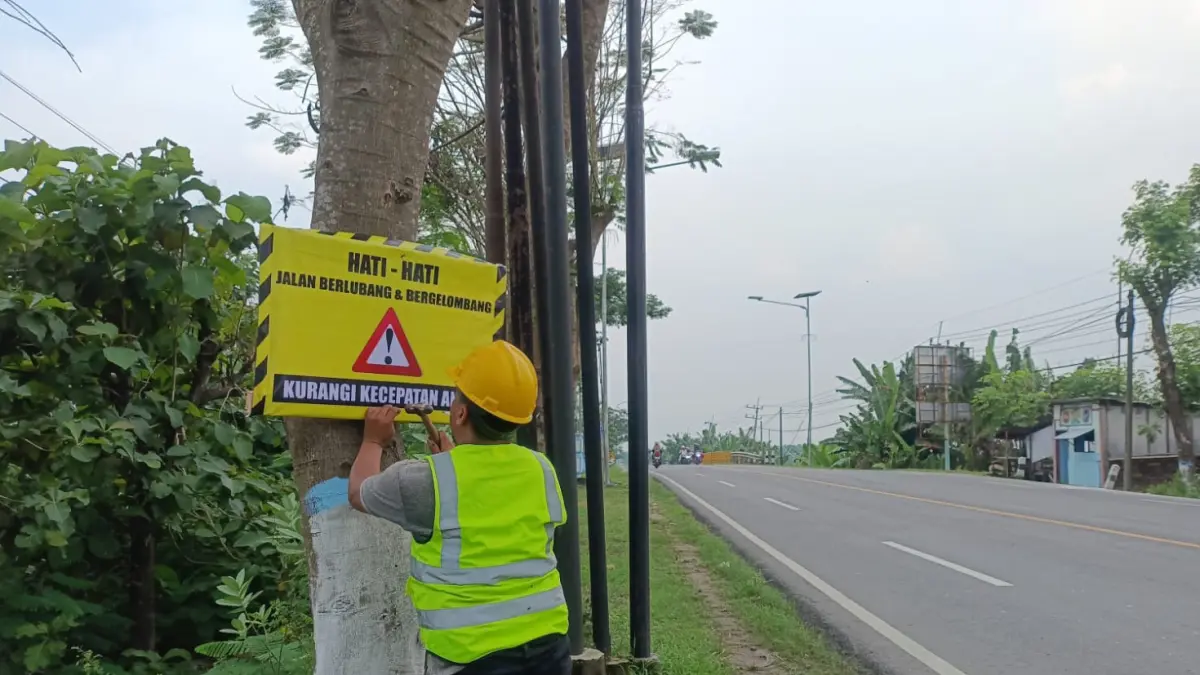 DIPASANGI RAMBU :Petugas BBJN Jatim-Bali memasang rambu di ruas Jalan Nasional Bojonegoro-Padangan. (ISTIMEWA/RADAR BOJONEGORO)
