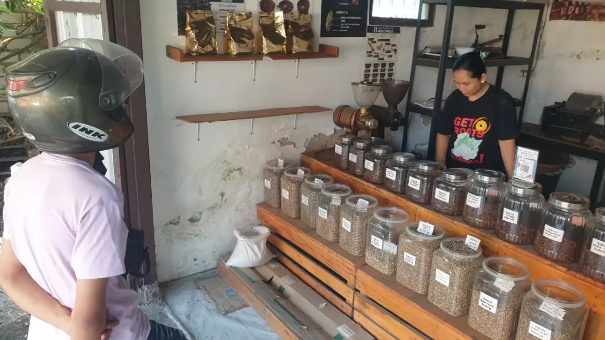 BANYAK PILIHAN: Toko Kopi Djadul, penjual biji kopi raw dan roasted hingga gilingan di depan Pemerintah Desa (Pemdes) Kalianyar, Kecamatan Kapas, Jumat (21/8) sore. Susi, pemilik gerai tersebut sedang melayani pembeli. (HAKAM ALGHIVARI/RADAR BOJONEGORO)