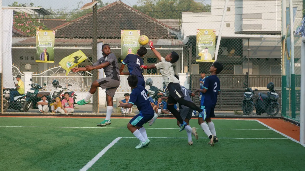BEREBUT DI UDARA: Pemain SMAN Rambipuji Yunus Fefanya Babingga (kiri), berebut bola atas dengan kiper SMKN 2 Jember dalam pertandingan semifinal Bahlil Mini Soccer Zona 10 Jember, kemarin sore (2/10). Pertandingan itu dimenangkan SMAN Rambipuji dengan skor 2-1. (SIDKIN ALI/RADAR JEMBER)
