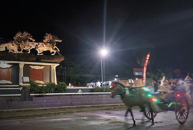 WISATA MALAM: Pengunjung menikmati wisata kereta kuda berkeliling di perkotaan Cepu, Blora. Tampak delman melintas di Patung Arjuna Wiwaha. (LUKMAN HAKIM/RDR.BLORA)