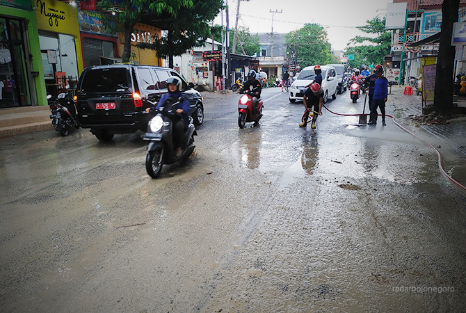 BAHAYAKAN PENGENDARA: Petugas damkar membersihkan lumpur di Jalan Pemuda, Senin sore (13/6). Dishub akan awasi mobilisasi tronton. (M. Nurcholis/RDR.BJN)