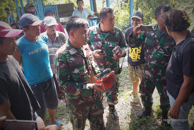 PERKAKAS PENTING: Petugas TNI bersama warga saat menemukan kotak oranye. Diprediksi black box pesawat T-501. Pencarian hingga di lereng bukit. (LUKMAN HAKIM/RDR.BJN)