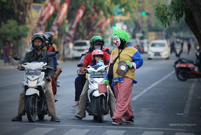 MENGGANGGU LALU LINTAS: Potret badut yang mengamen di salah satu traffic light di jalan protokol. (ANJAR DWI PRADIPTA/RDR.LMG)