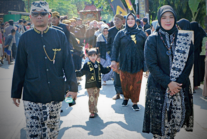 MERAKYAT: Kepala Desa/Kecamatan Malo Sujito Bersama istrinya Anis Musyarofah berjalan bersama warga dalam rangka grebek suro. (Yuan Edo/RDR.BJN)