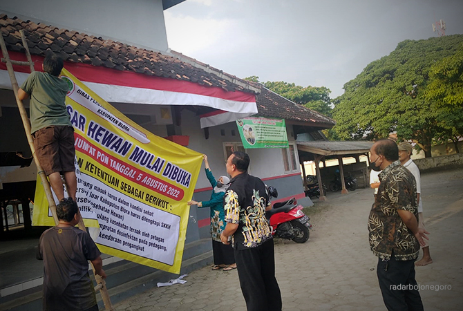 TETAP KETAT: Petugas mengambil banner pengumuman penutupan pasar hewan di Kelurahan Tegalgunung, Kecamatan Blora. (Lukman Hakim/RDR.Blora)