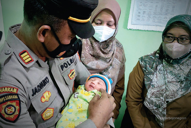 SEHAT: Kapolsek menggendong bayi yang ditemukan warga Desa Sumberarum. (Istimewa For RDR.BJN)
