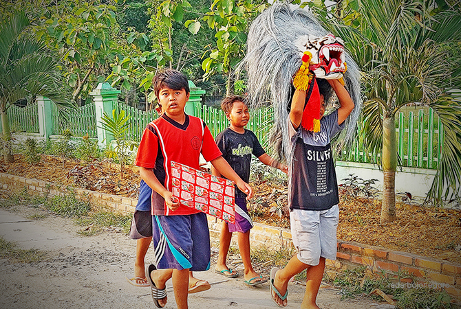 GANDRUNG SENI: Anak-anak berjalan di tepi Jalan Kecamatan Jiken. Membawa topeng barongan dan bermain bersama di lapangan. (LUKMAN HAKIM/RDR.BLORA)