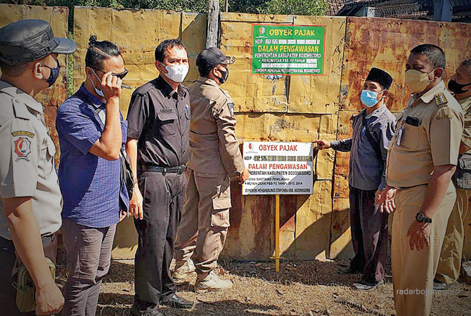 BERBURU PAJAK: Petugas bapenda memasang stiker di bangunan warga masih nunggak PBB. (Istimewa For RDR.BJN)