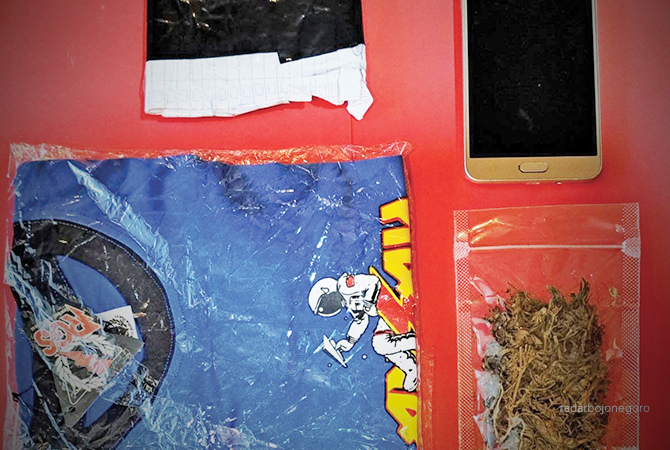 BARANG BUKTI: Ganja seberat 12,85 gram, kaus berwarna biru, dan handphone Samsung yang diamankan petugas. (M. GAMAL A/RDR.LMG)