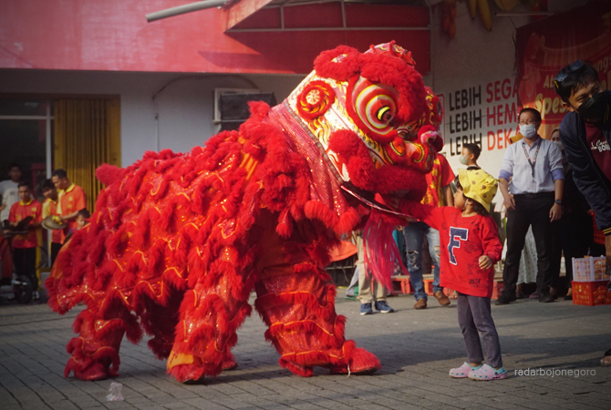 JELANG IMLEK: Seorang anak tampak dekat dengan barongsai saat beratraksi di halaman waralaba di Jalan Teuku Umar, Bojonegoro kemarin (21/1). (YUAN EDO/RDR.BJN)
