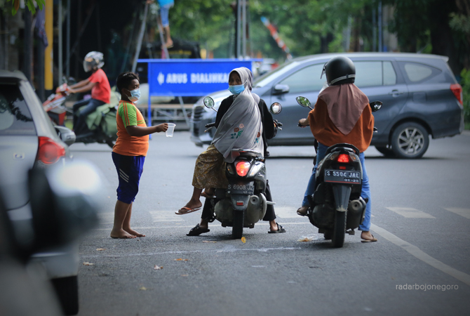 HASILNYA LUMAYAN: Seorang pengemis menyodorkan gelas plastik dengan harapan diberi uang, kepada pengendara motor yang lewat. (ANJAR DWI PRADIPTA/RDR.LMG)