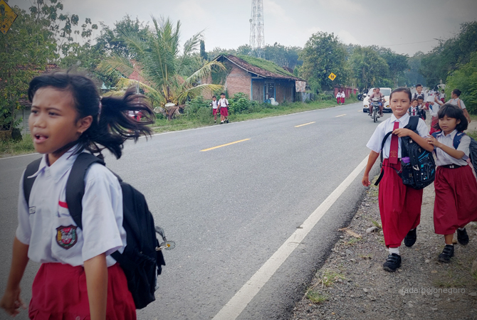 BELAJAR: Siswa-siswi SDN Jiken pulang sekolah menyusuri jalanan aspal Blora-Cepu. (LUKMAN HAKIM/RDR.BLORA)