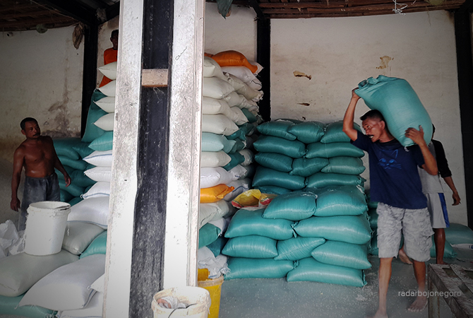 FLUKTUATIF: Pekerja sedang mengangkat beras di dalam karung di Pasar Banjarejo, harga bahan pokok di lapangan fluktuatif. (DEWI SAFITRI/RDR.BJN)
