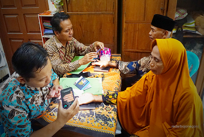 SCAN: Petugas Kemenag Bojonegoro memfoto scan tangan jemaah haji usia lanjut kemarin (30/3). (YUAN EDO/RDR.BJN)