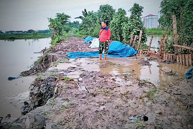 RAWAN JEBOL: Petugas BPBD Lamongan meninjau titik tanggul Kali Plalangan yang ambles. (M. GAMAL AYATULLAH/RDR.LMG)