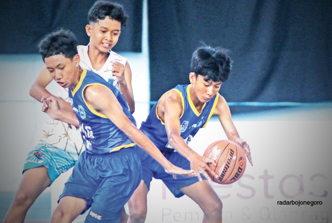 DUA LAWAN SATU: Pemain basket SMPN 2 Lamongan menguasai bola pada laga final Bupati Cup Basketball Competition 2023 kemarin di Sport Center Lamongan. (ANJAR DWI PRADIPTA/RDR.LMG)