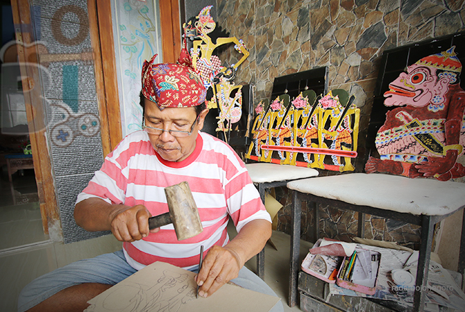 CEKATAN: Rais Putro saat memahat gambar wayang berbahan kertas karton di teras rumahnya, kemarin (16/6). (ANJAR DWI PRADIPTA/RDR.LMG)