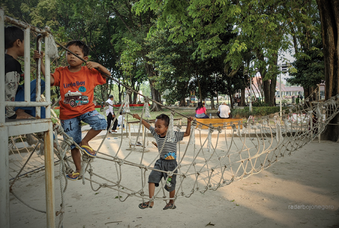 UJI KETANGKASAN: Anak-anak sedang bermain jembatan tali untuk melatih ketangkasan di Alun-Alun Bojonegoro Kemarin (11/6). Setiap hari Minggu dan hari libur pusat kota ini selalu ramai pengunjung. (WAHYU DHANI ALFIANSYAH/RDR.BJN)