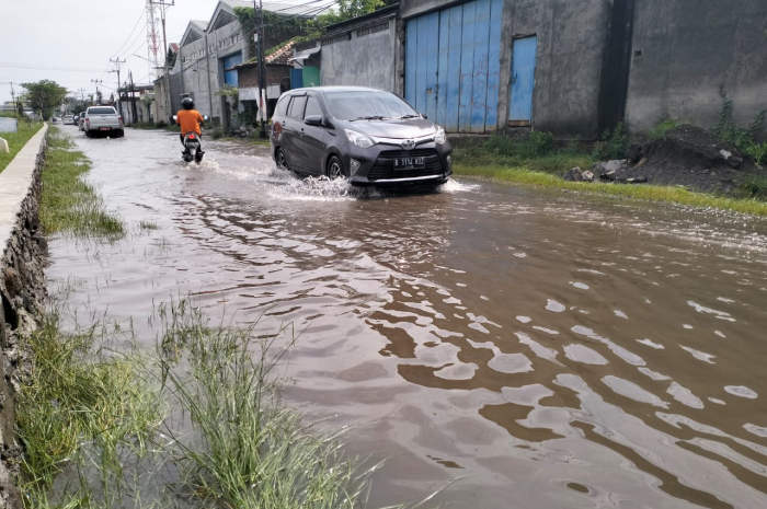 Pengguna jalan melintasi jalan Muktiharjo Raya yang tergenang banjir.