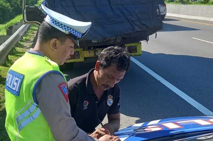 Polisi sedang menilang salah seorang pengendara mobil yang membawa barang dengan ketinggian berlebih.