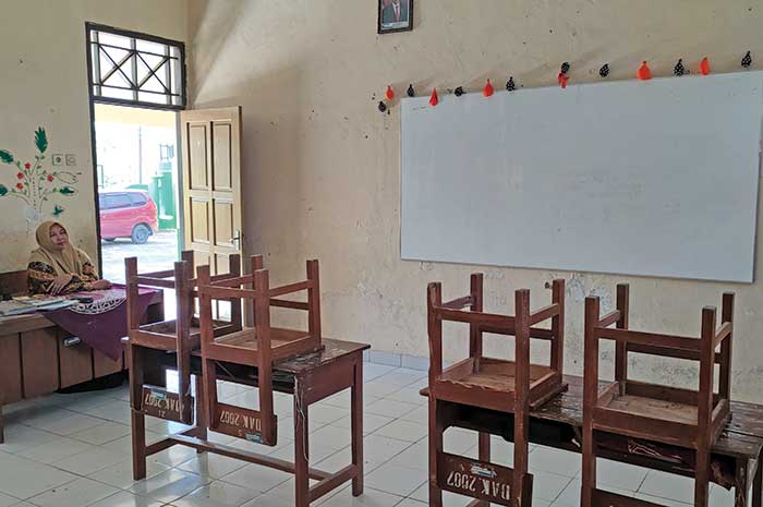 Guru kelas 1 SDN Kranggan duduk termenung di ruang kelas yang biasa digunakannya mengajar.