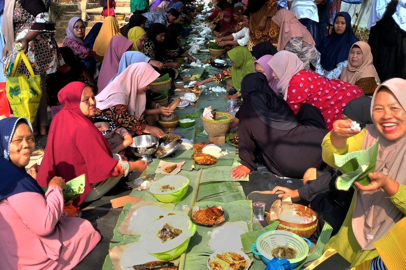 MONGGO DHAHAR : Warga Kampung Kuripan RW 1 Kelurahan Wonolopo menikmati makanan yang mereka bawa di makam Sentono Kanjeng Mas Bupati RM. Haryo Sumantri Jumat (28/7) siang. (NUR CHAMIM/JAWA POS RADAR S