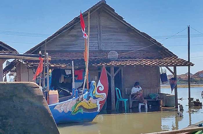 Seorang warga terlihat sedang duduk bersantai di rumah yang tidak layak di kawasan kumuh pesisir Kecamatan Kendal.&nbsp;