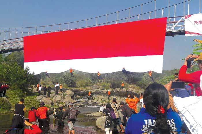 Siswa SMK Mipha Parakan mengibarkan bendera raksasa di Jembatan Sangkil, Parakan, Kabupaten Temanggung, Kamis (10/8).