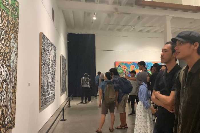 Pengunjung menikmati lukisan dalam pameran