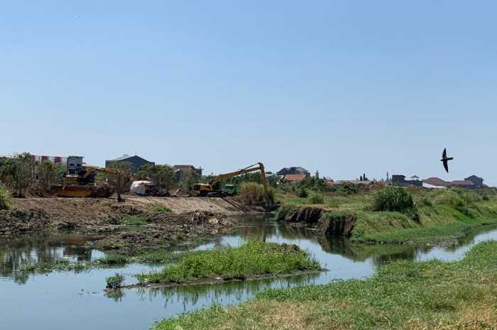 Dua alat berat terlihat sedang mengeruk sendimentasi yang menutupi aliran sungai Banjir Kanal Timur di sekat Jembatan Kartini, Jumat (1/9).