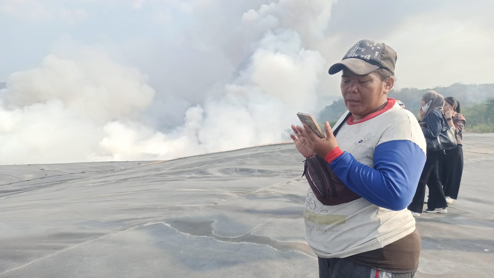 Zubaidah sibuk dengan handphone miliknya. Sesekali juga menelpon dan berbicara dengan seseorang terkait kondisi bedeng yang terbakar.