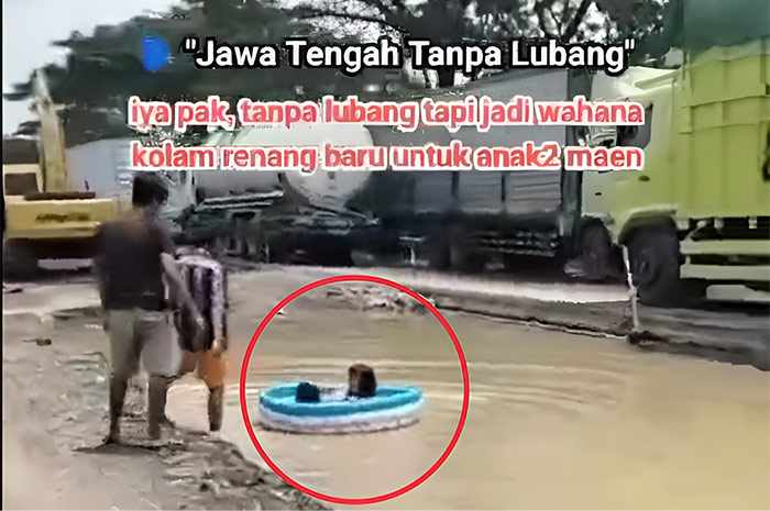 Seorang anak menggunakan pelampung air di perbaikan Jalan yang tergenang air keruh di Pantura Juwana