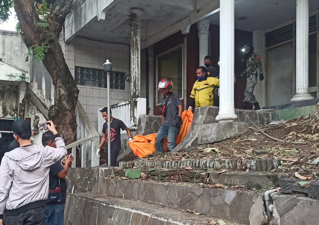 Petugas dibantu warga mengevakuasi mayat tanpa identitas di rumah kosong jalan Sriwijaya Semarang. (M Hariyanto/Jawa Pos Radar Semarang)