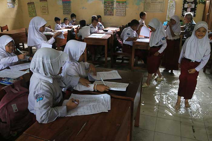 Para siswa SD Negeri Muktiharjo Lor mengerjakan PAS di tengah banjir, Selasa (28/11). NUR CHAMIM/JAWA POS RADAR SEMARANG