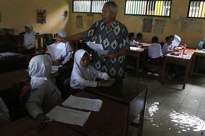 Para siswa SD Negeri Muktiharjo Lor mengerjakan PAS di tengah banjir, Selasa (28/11). NUR CHAMIM/JAWA POS RADAR SEMARANG