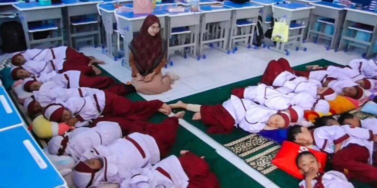 Guru SD Muhammadiyah 4 Zamzam Sidoarjo sedang memantau para siswa yang tengah tidur siang bersama di kelas. (Sumber: muhammadiyah.or.id)