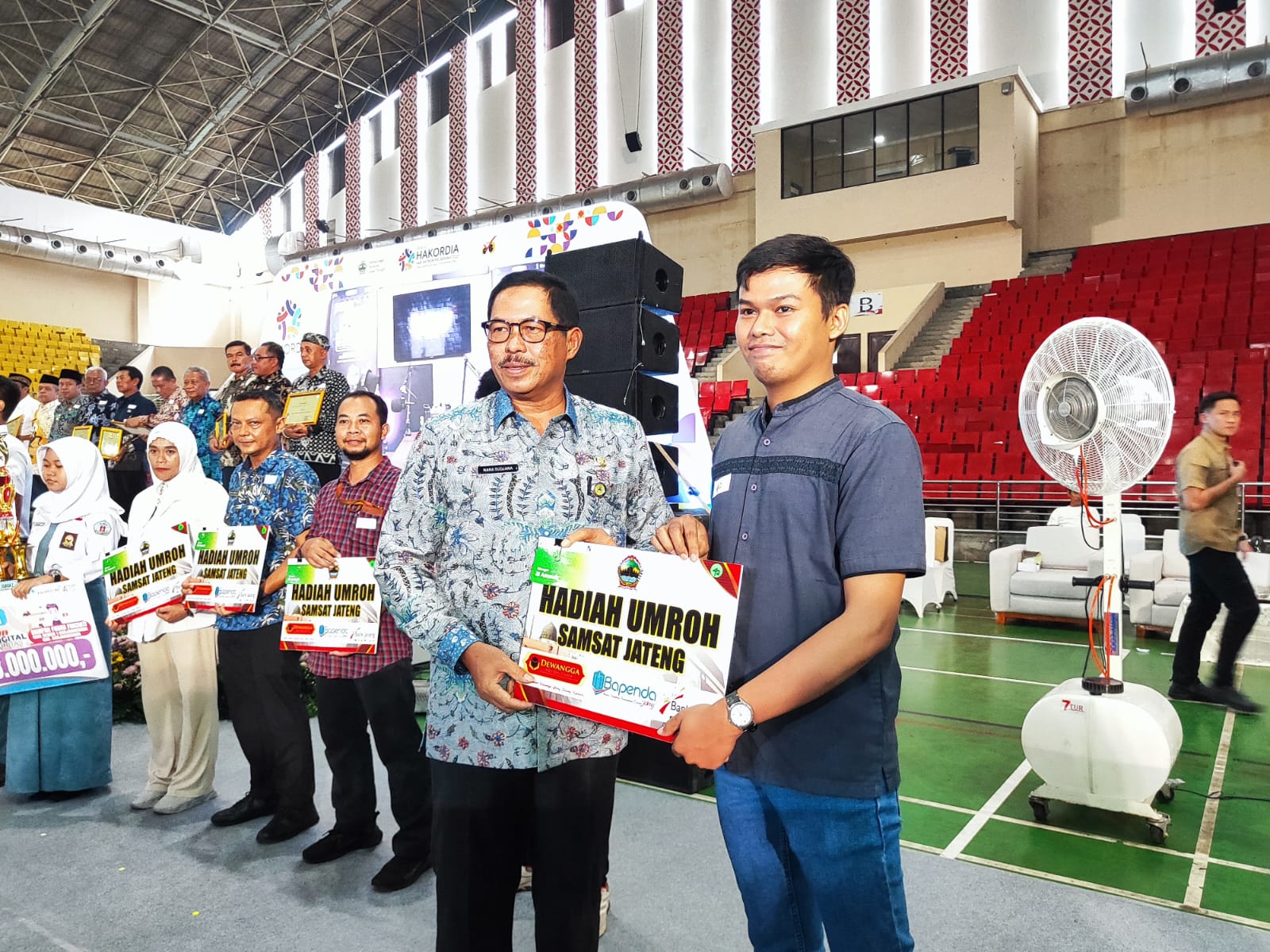 Pj Gubernur Jawa Tengah Nana Sudjana (kiri) memberikan hadiah umroh gratis dari Bapenda Jateng untuk masyarakat yang patuh pajak di Gor Jatidiri, Rabu (5/12).