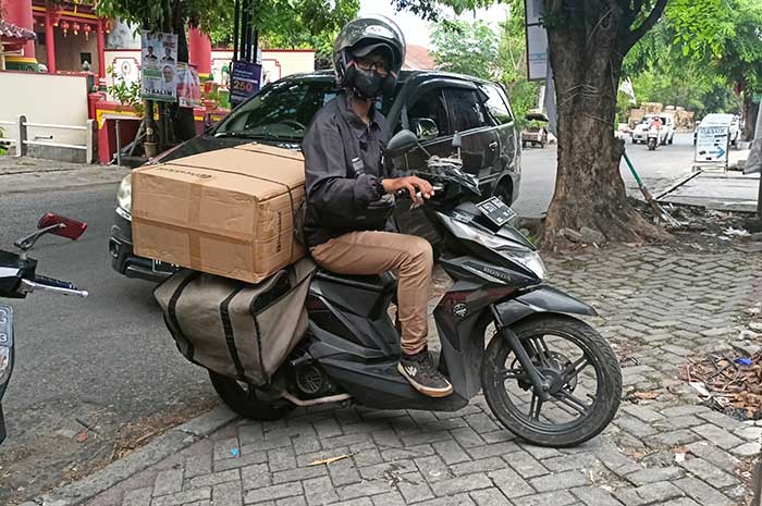 Salah satu kurir ekspedisi di Kota Semarang ketika mengirimkan barang yang ukurannya besar dan terpaksa tetap harus diantarkan. (ADENNYAR WYCAKSONO/JAWA POS RADAR SEMARANG)