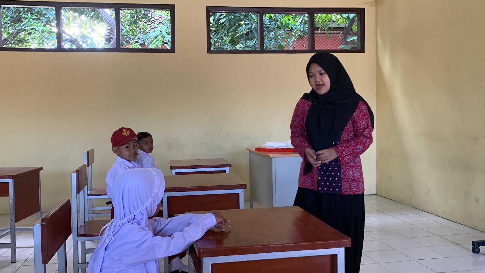 Ilustrasi seorang  guru SD saat memberikan pembelajaran terhadap siswanya di dalam kelas.