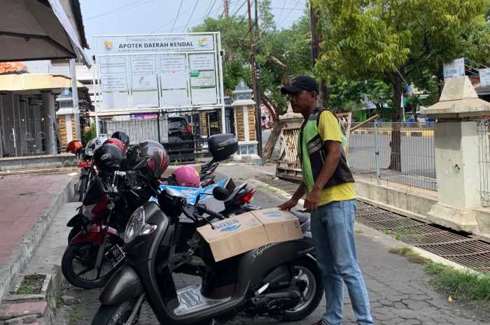 Seorang juru parkir tampak menata sepeda motor di lingkungan GOR Bahurekso Kendal.&nbsp;DEVI KHOFIFATUR RIZQI/ JAWA POS RADAR SEMARANG